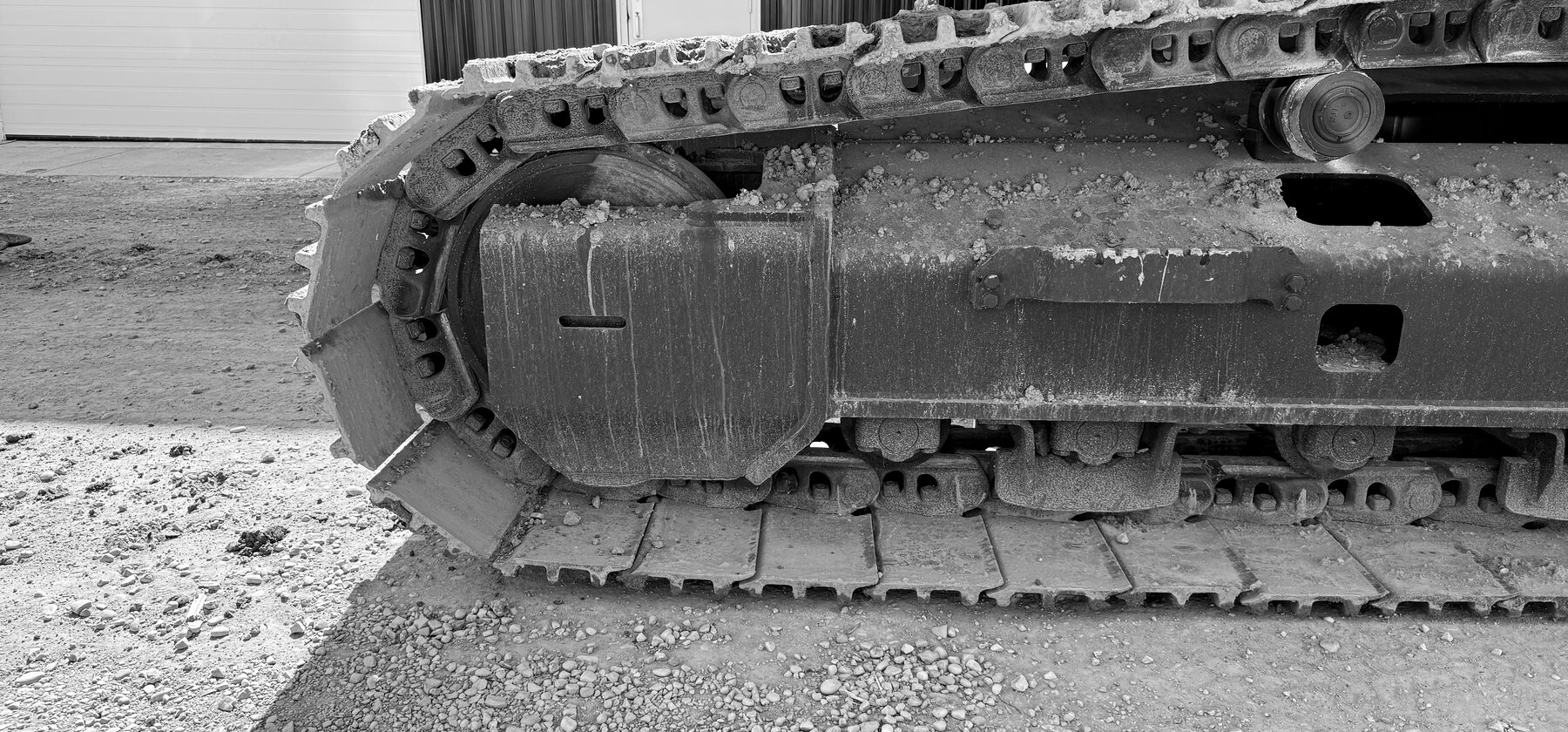 A steel track chain wrapped around a drive sprocket on an excavator undercarriage