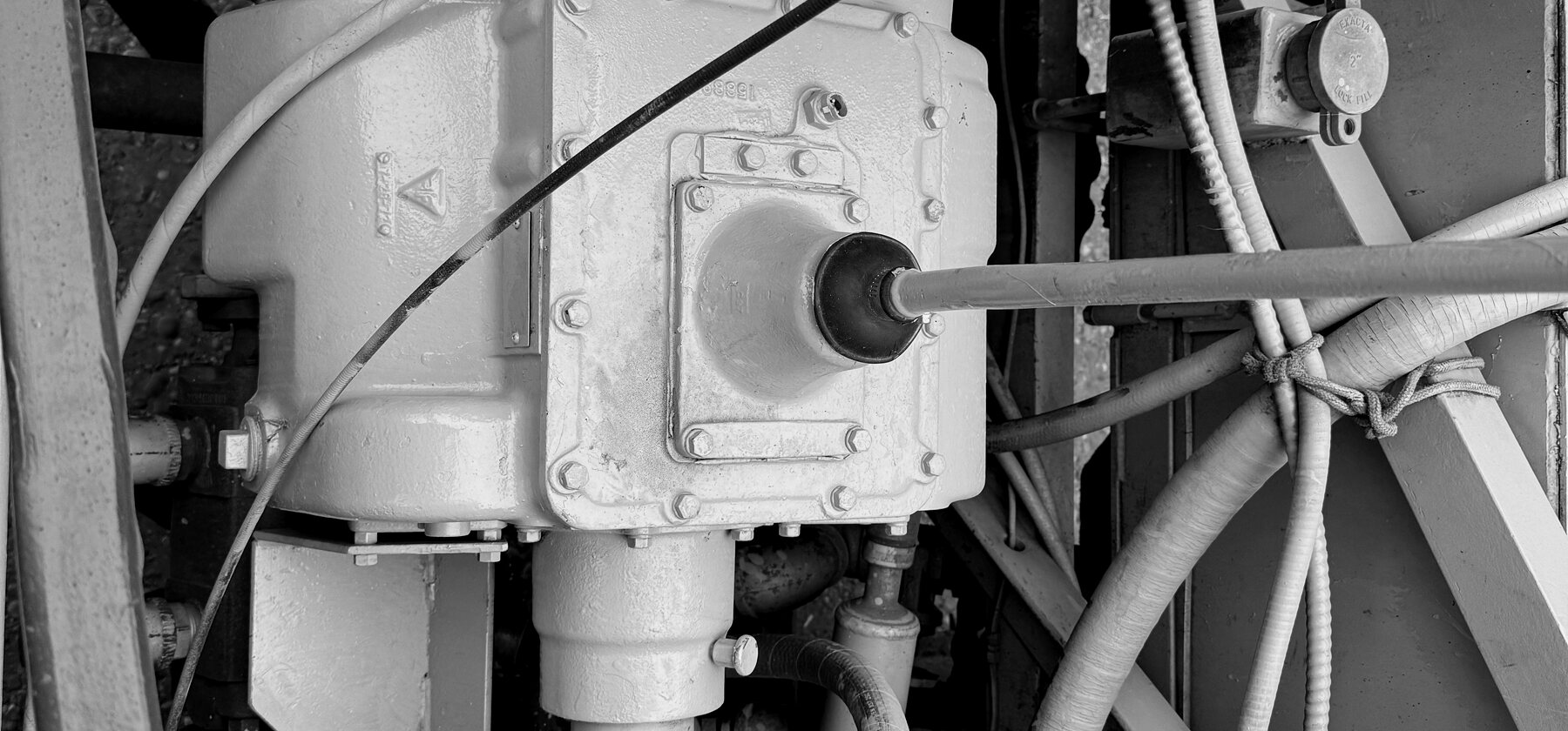 A gearbox housing and drive shaft under a wheel trencher's engine cover