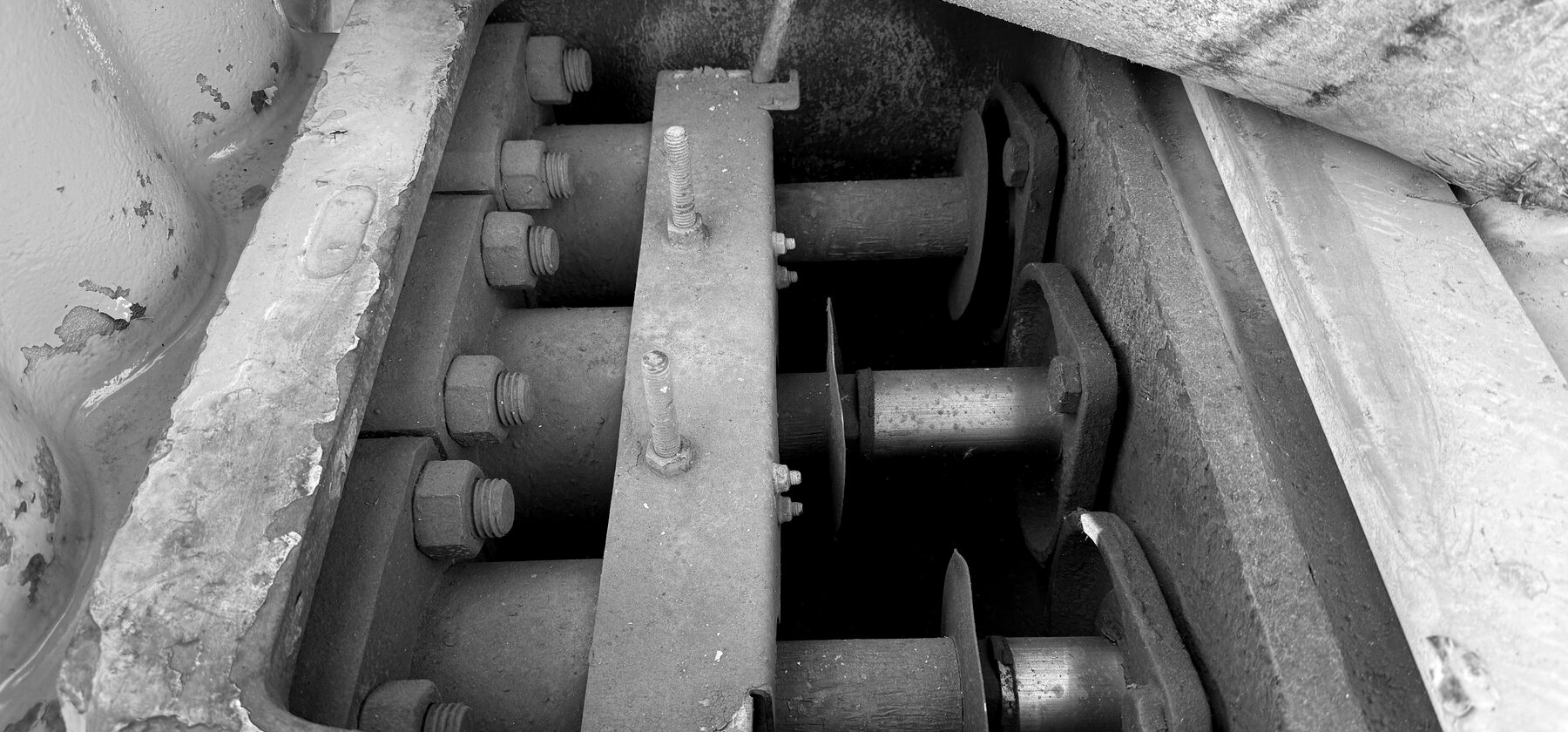 Rusted retaining bolts and steel pins inside a drill's open gearbox access panel