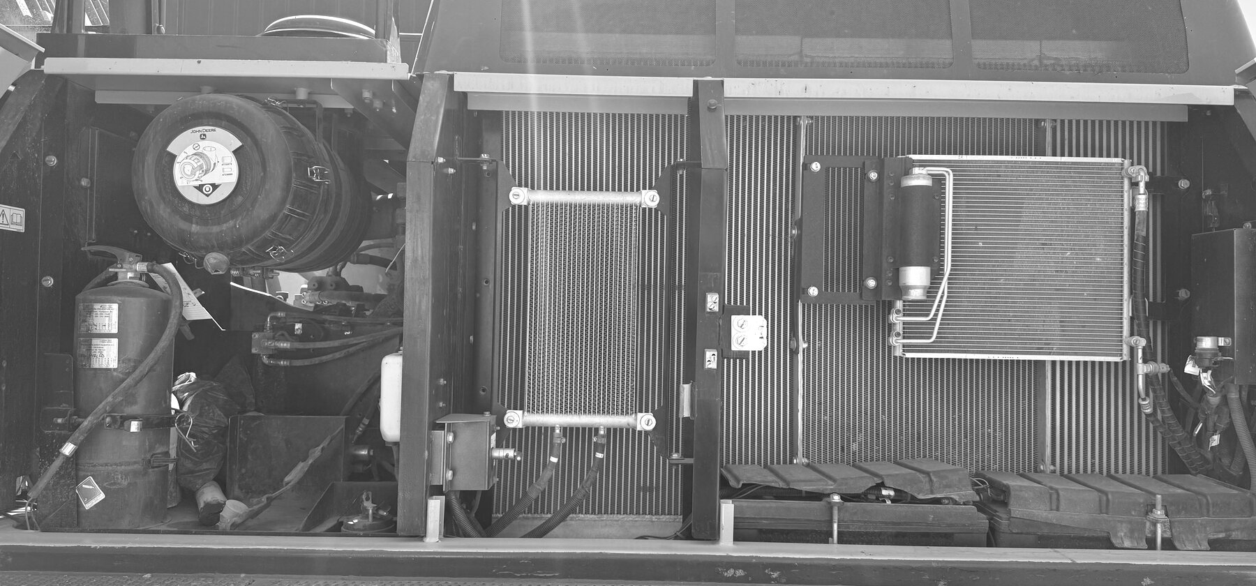 Twin radiators and a fire extinguisher inside an open excavator engine bay