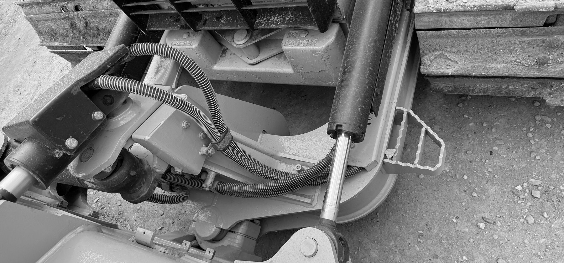 A dozer blade tilt cylinder and hydraulic hoses beside a stacked track chain