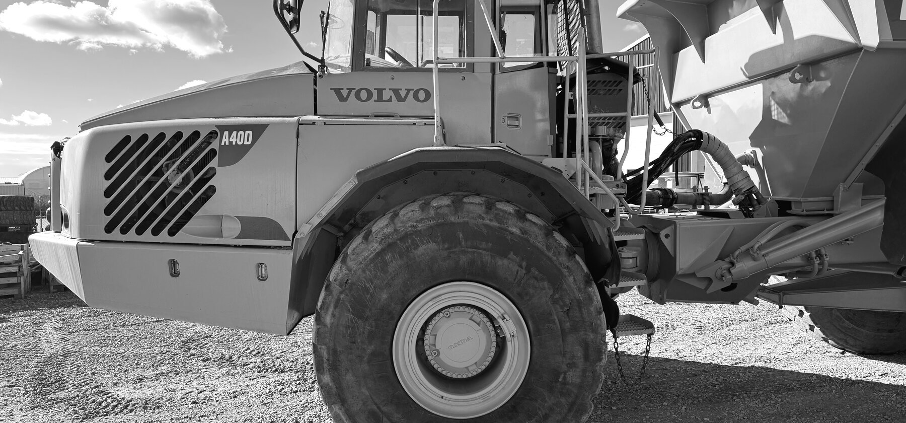A Volvo A40D rock truck in the yard, cab and front wheel in close profile with the dump box raised behind