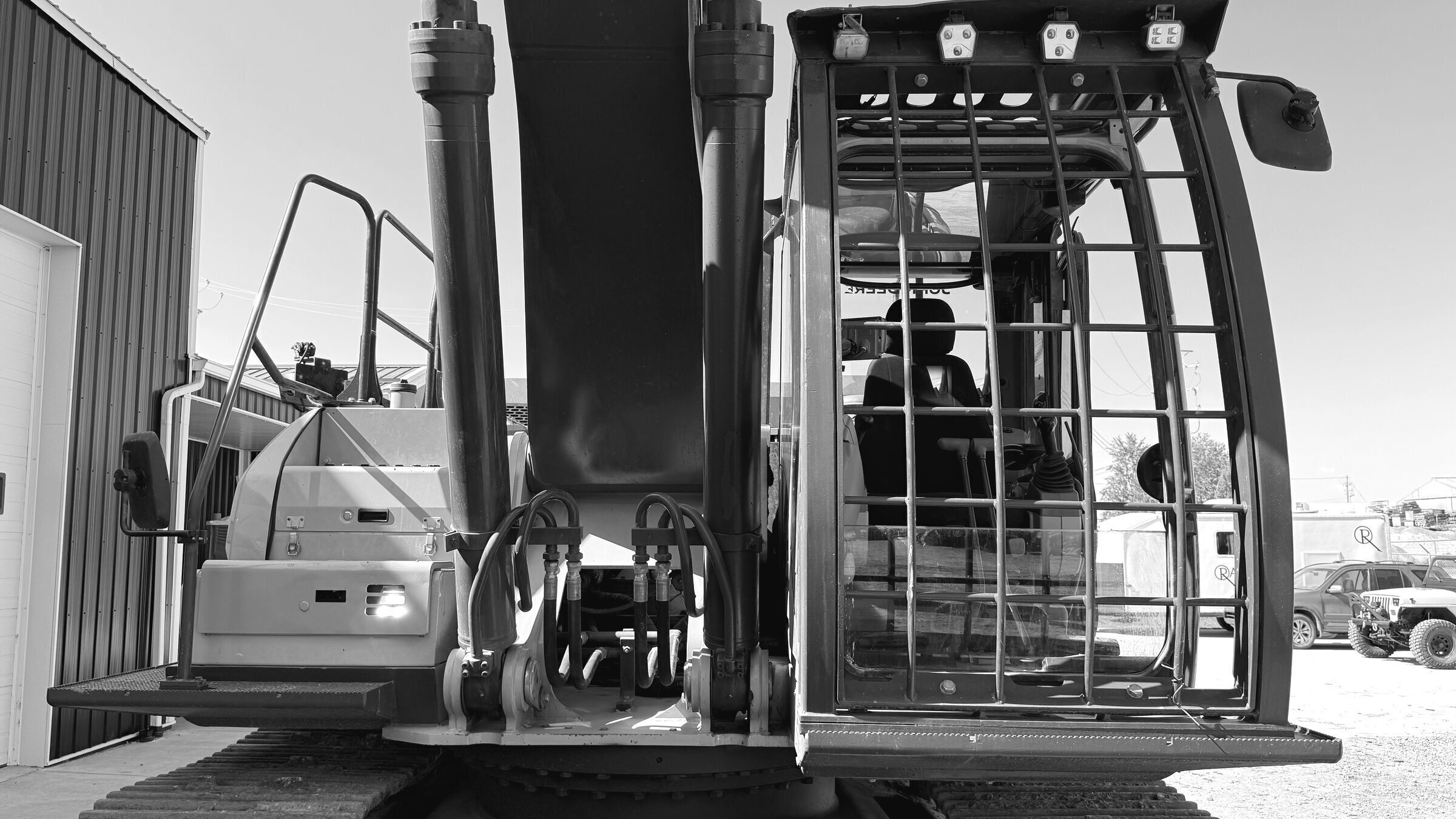 An excavator cab seen from the front, the guarded glass and the operator's seat behind it