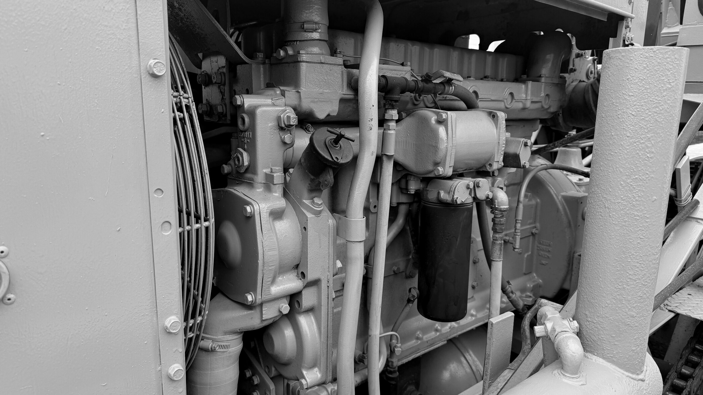 A tractor engine bay: the manifold, hoses and fittings between the fan shroud and the frame rail